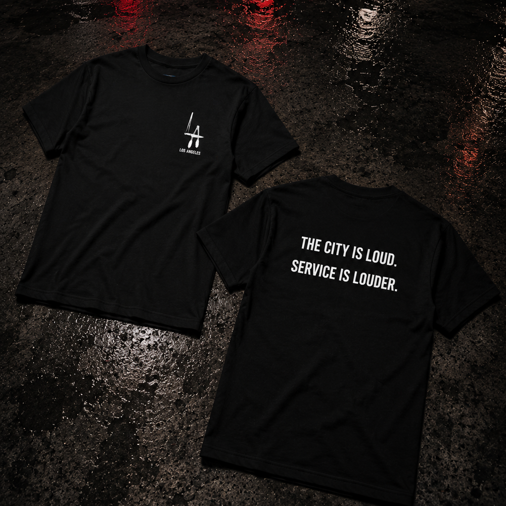 Two black t-shirts on a wet pavement with a quote printed on one of them.