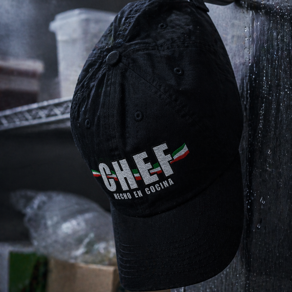 Black cap with 'CHEF' text hanging on a dark surface